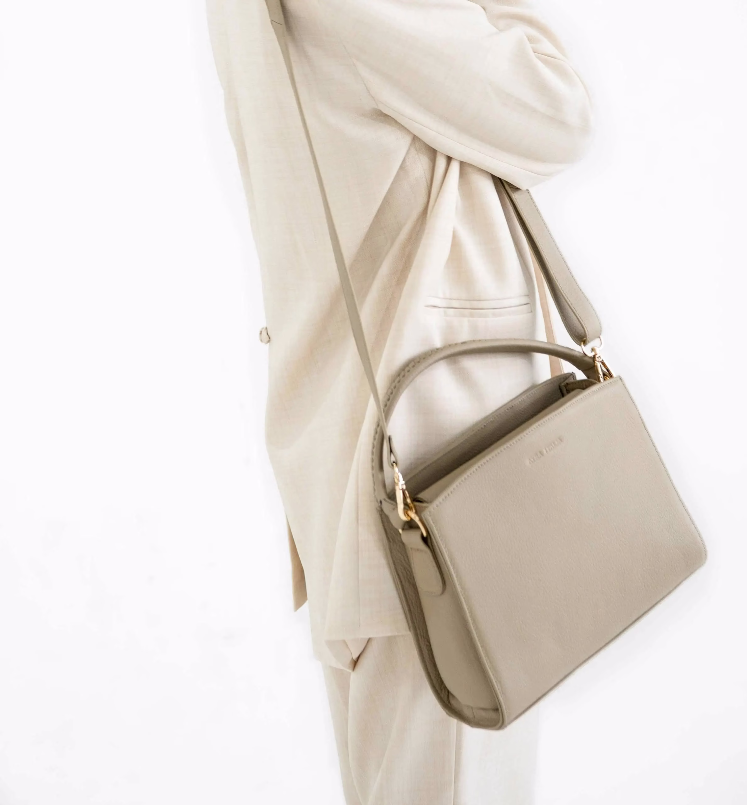 ベージュの革製ショルダーバッグを持った立っている女性